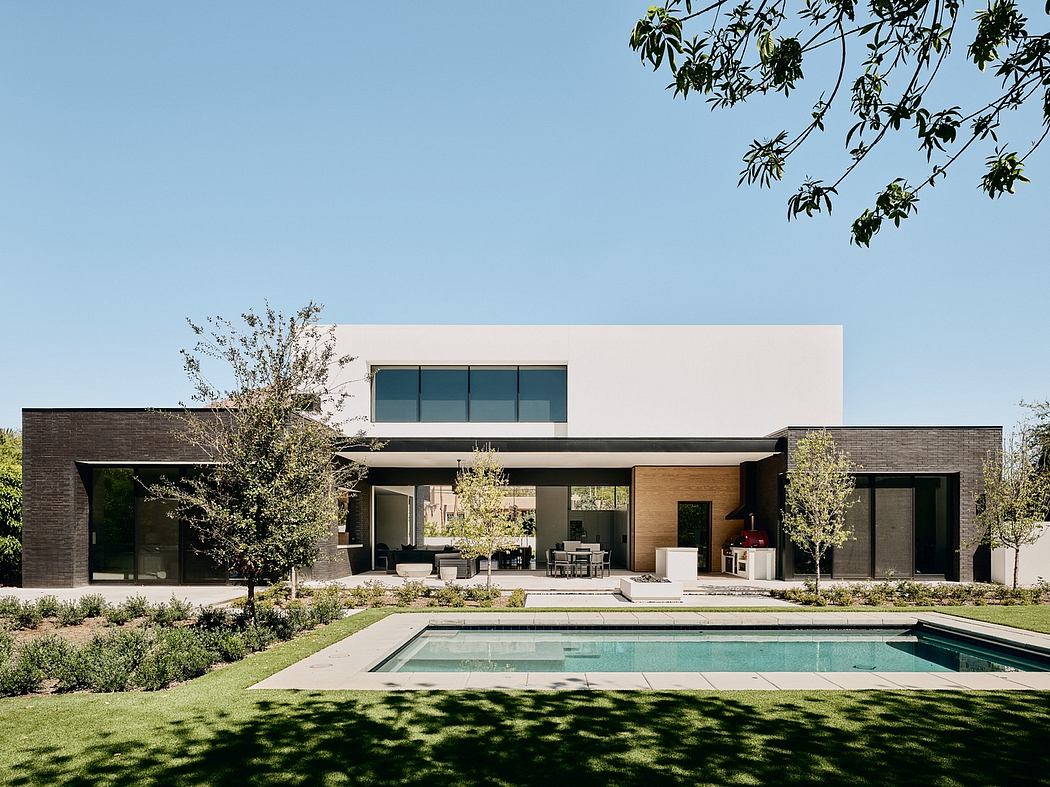 A modern, single-story home with a flat roof, large windows, and a pool in the foreground.