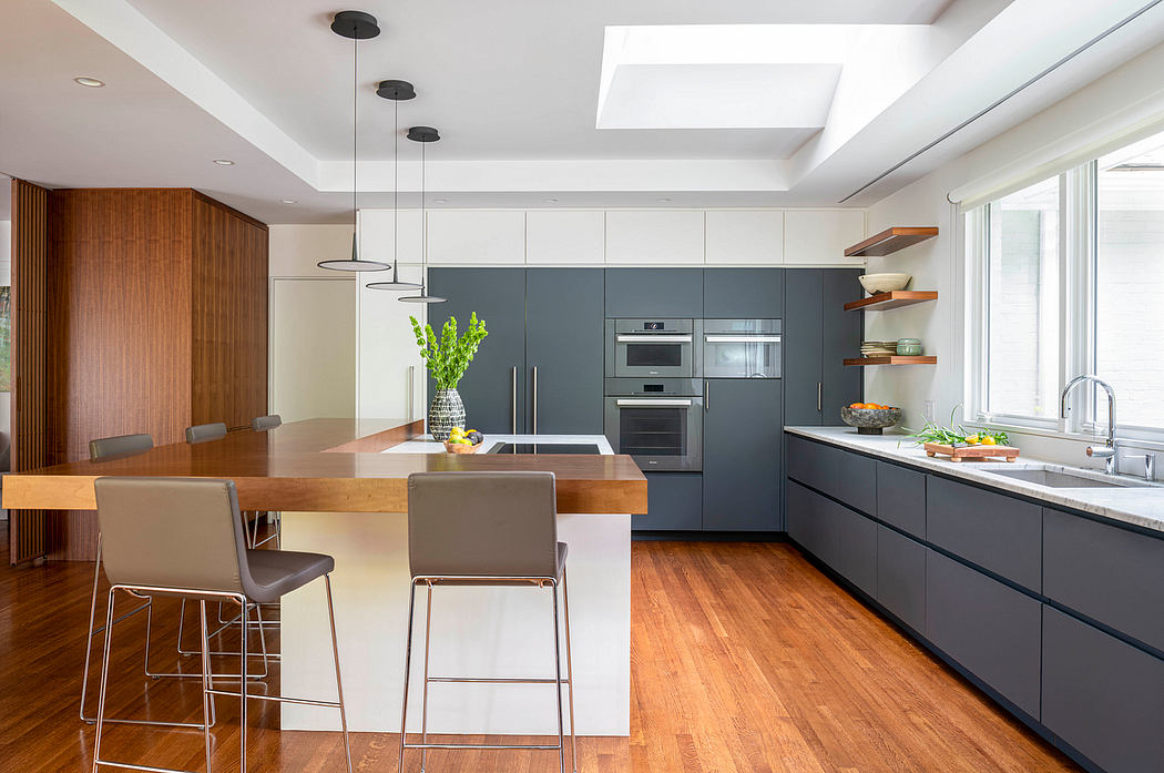 Modern kitchen with sleek gray cabinets, wooden dining table, and pendant lighting.