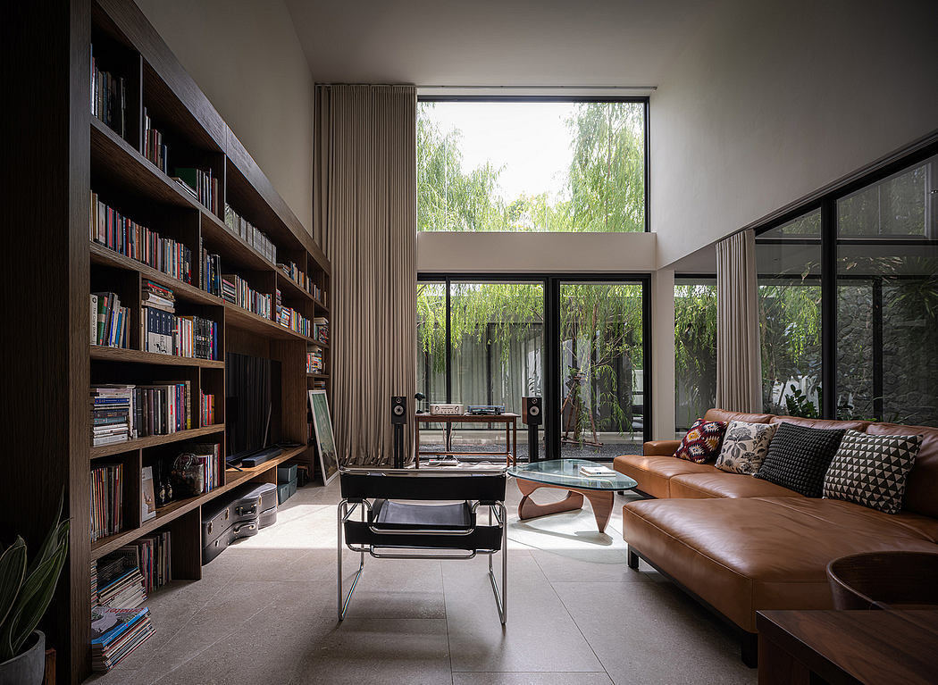 Spacious living room with floor-to-ceiling windows, built-in bookshelves, and leather sofa.