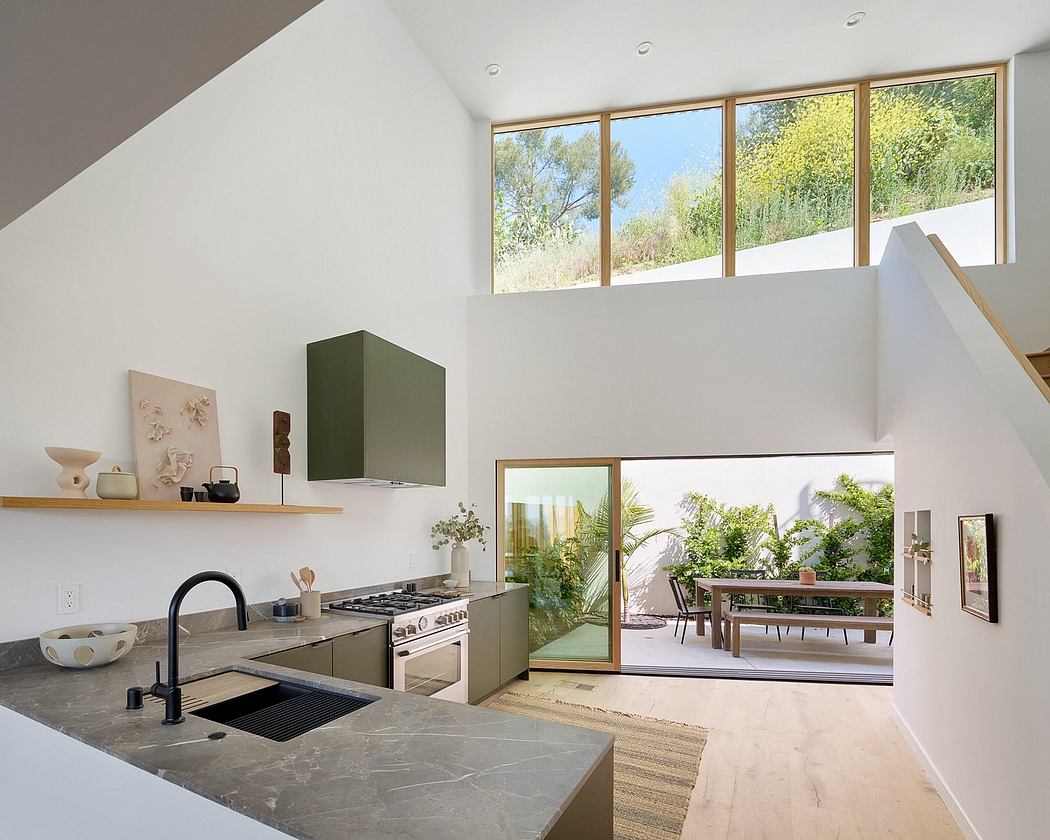 Modern kitchen with floor-to-ceiling windows, sleek cabinetry, and glimpse of outdoor patio.