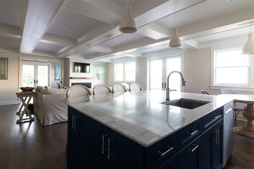 Spacious open-concept kitchen with marble countertops, dark cabinetry, and pendant lighting.