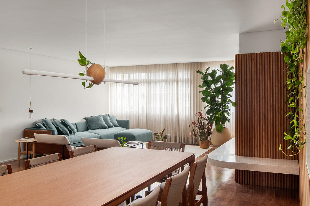 A modern, minimalist living room with a wooden dining table, plush sofa, and lush indoor plants.