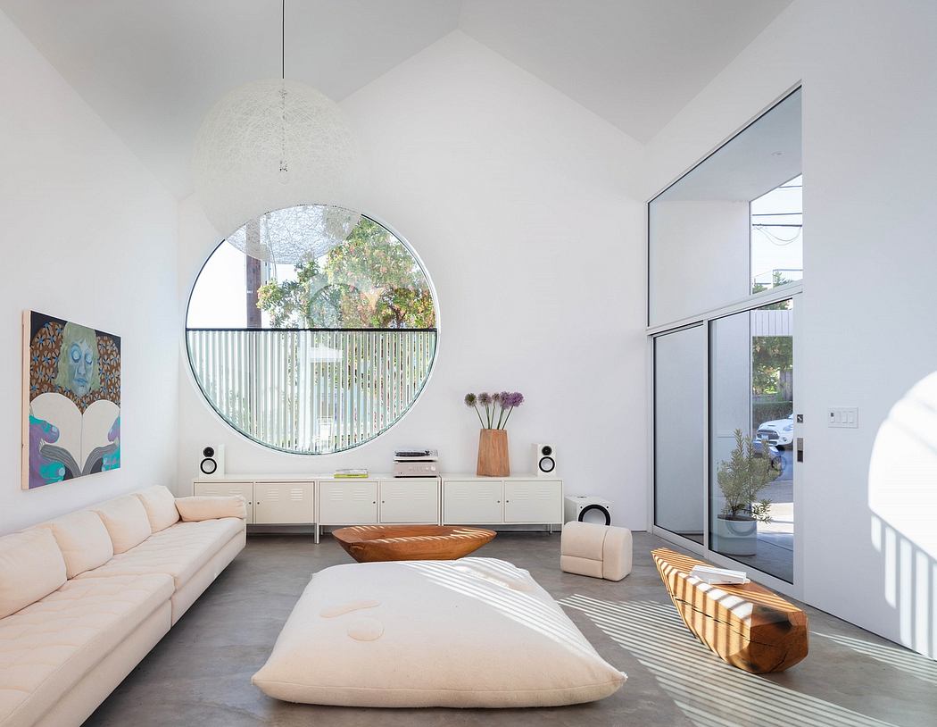 Airy, minimalist living room with large window, circular mirror, and modern furniture.