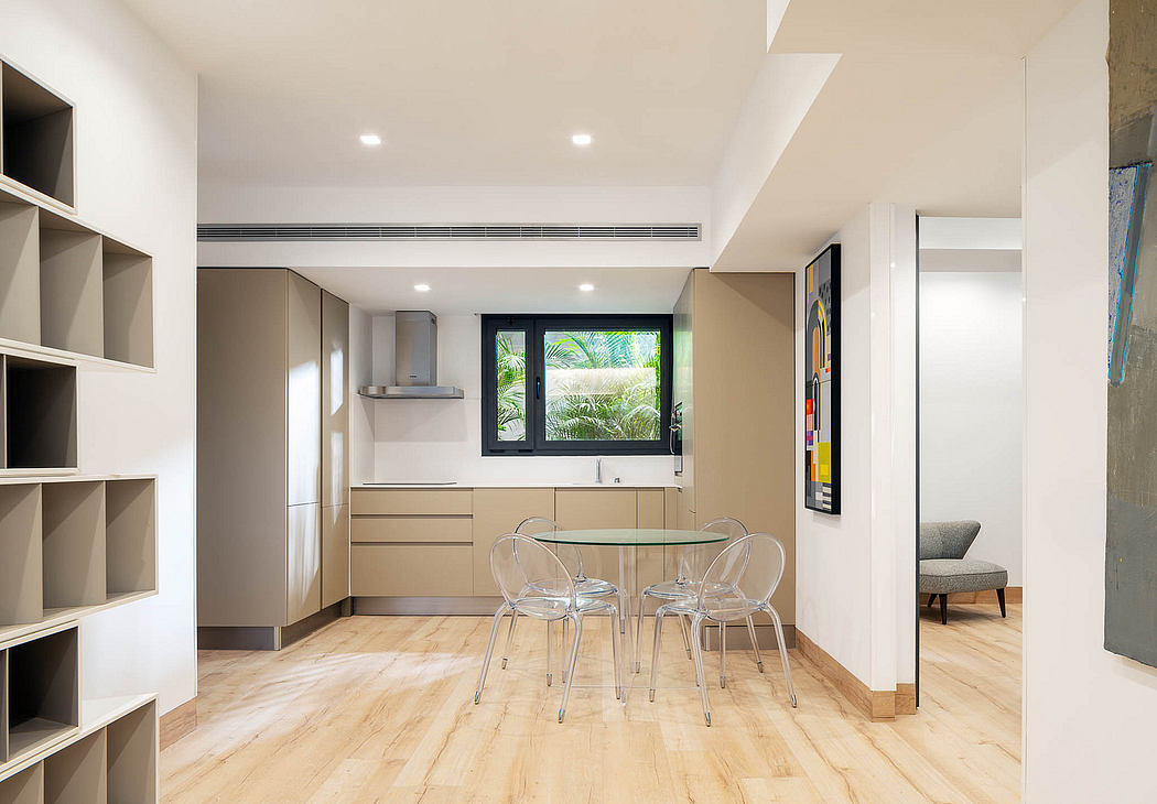 Modern open-concept kitchen with built-in storage, glass-top dining table, and lush tropical view.