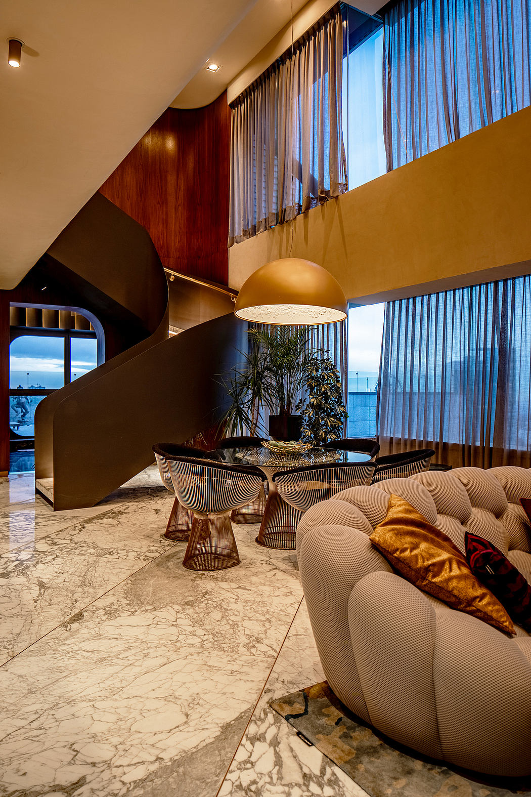 A luxurious hotel lobby with warm lighting, plush furnishings, and striking architectural features.