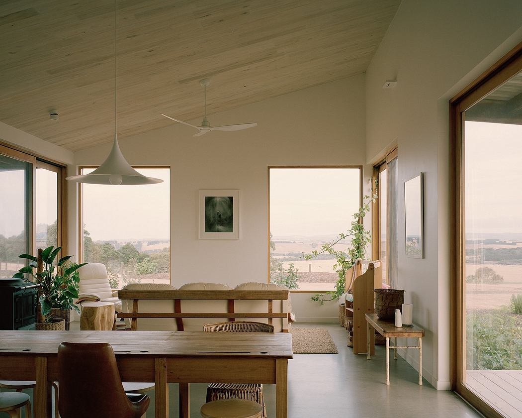 Spacious living room with natural light, wooden ceiling, and minimalist furniture.