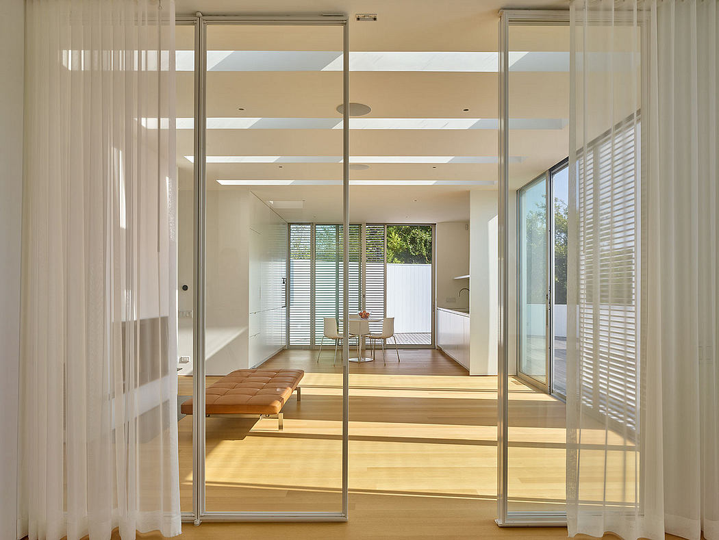 Expansive open floor plan with wood floors, glass walls, and minimalist decor.