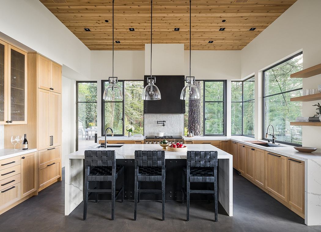 Spacious modern kitchen with wooden ceiling, large windows, marble counter, and industrial-style lighting.