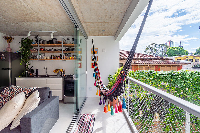 Open-concept kitchen with hammocks, shelving, and views of lush outdoor foliage.