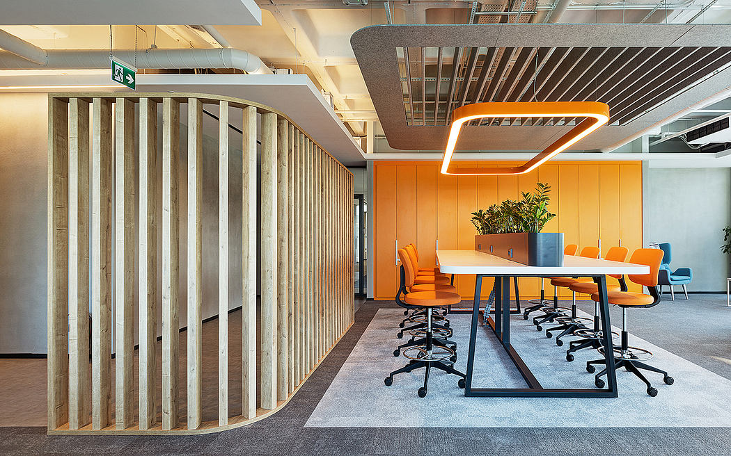 Sleek, modern office space with wooden dividers, vibrant orange chairs, and geometric lighting.