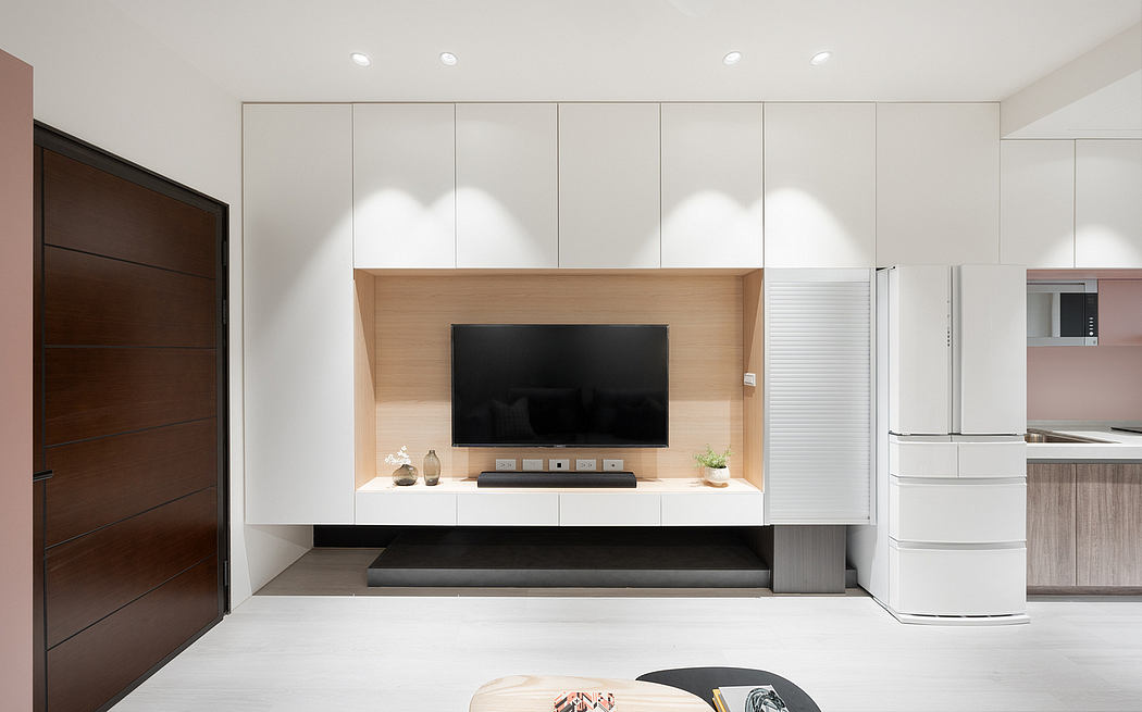 A minimalist, contemporary living space featuring a sleek TV cabinet, built-in cabinetry, and integrated appliances.