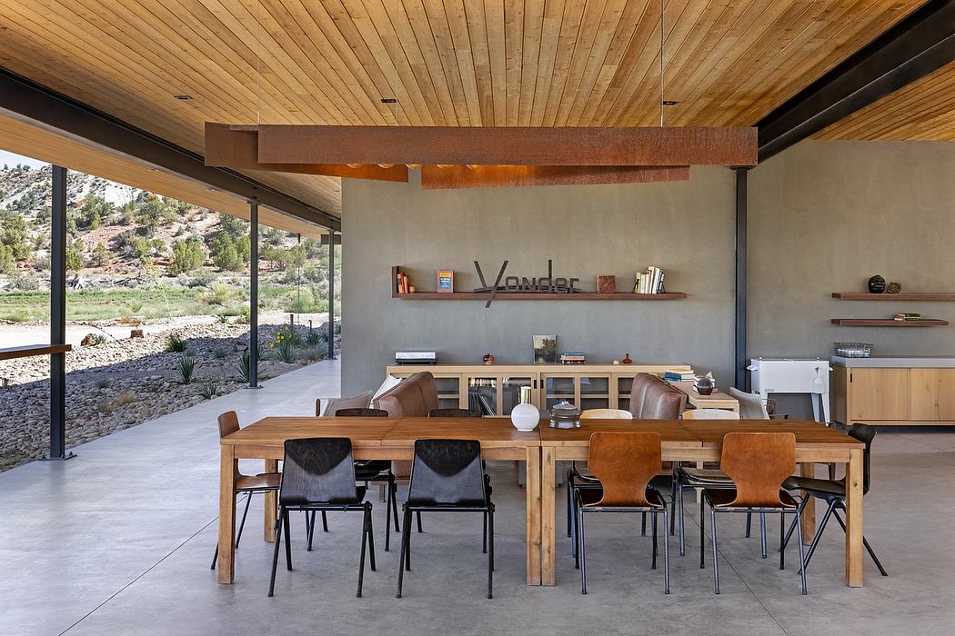 Interior with wood ceiling, beams, and table; exposed concrete walls and floor; mid-century furnishings.