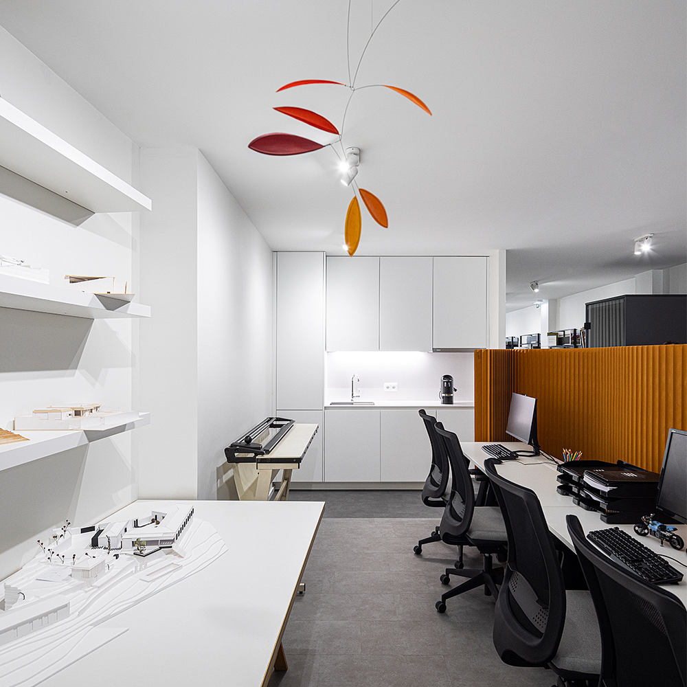 Sleek, modern office space with minimalist furnishings and a colorful mobile sculpture.