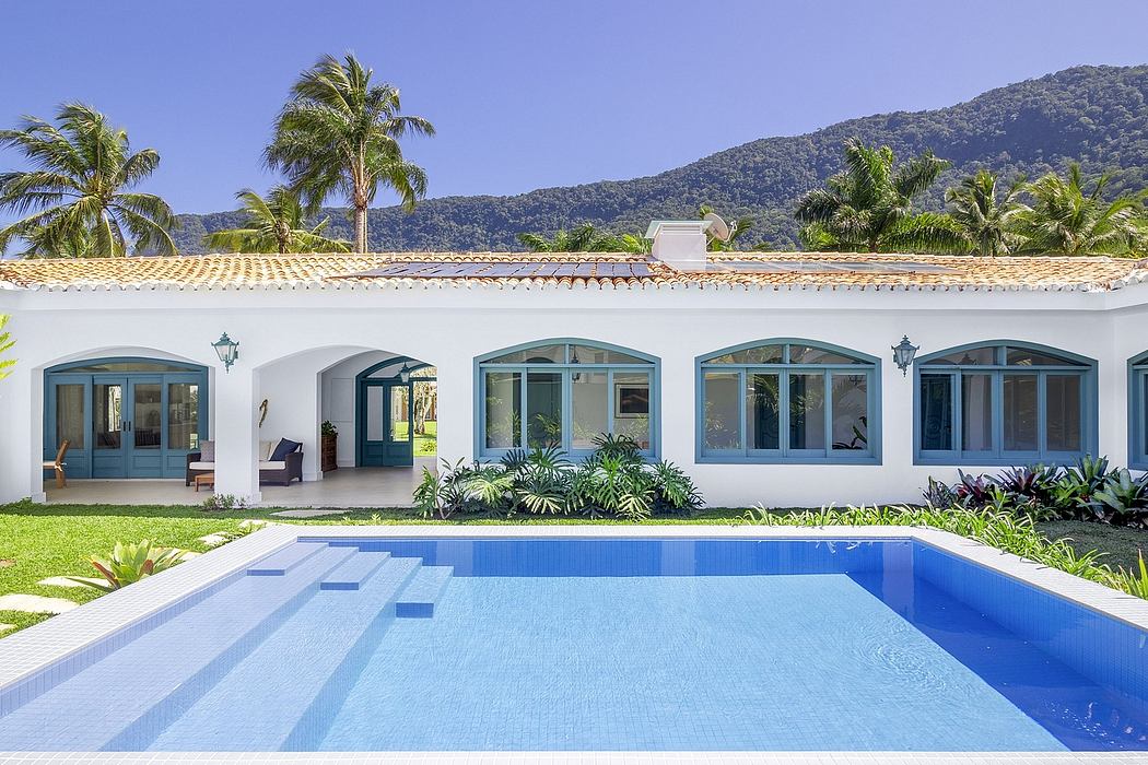 A beautiful Spanish colonial-style villa with an inviting pool, surrounded by lush greenery.