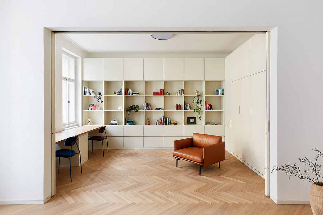 Minimalist interior with built-in shelving, hardwood herringbone floor, and leather armchair.