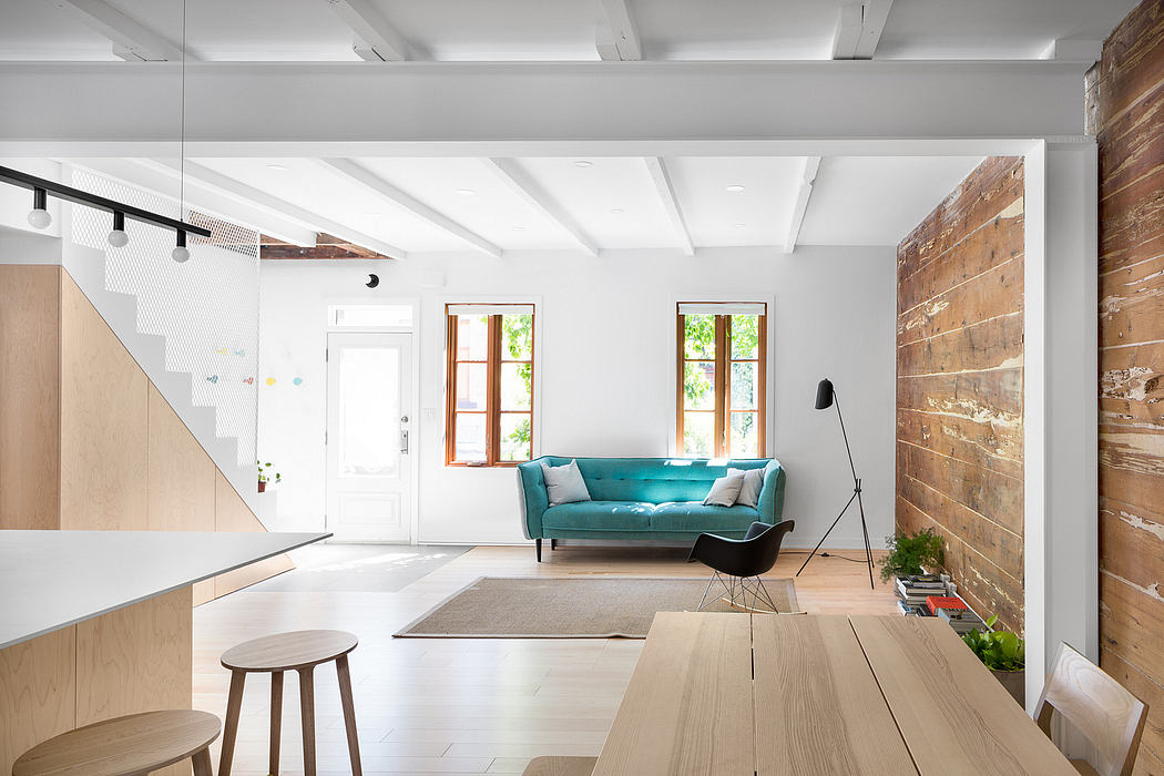 Bright, modern open-plan interior with wood, brick, and teal furnishings.