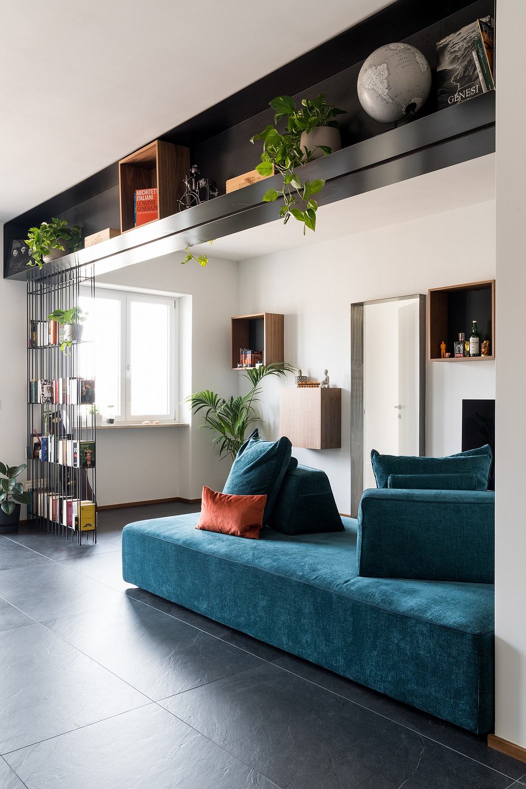 Cozy living room with built-in shelves, potted plants, and plush teal sofa.