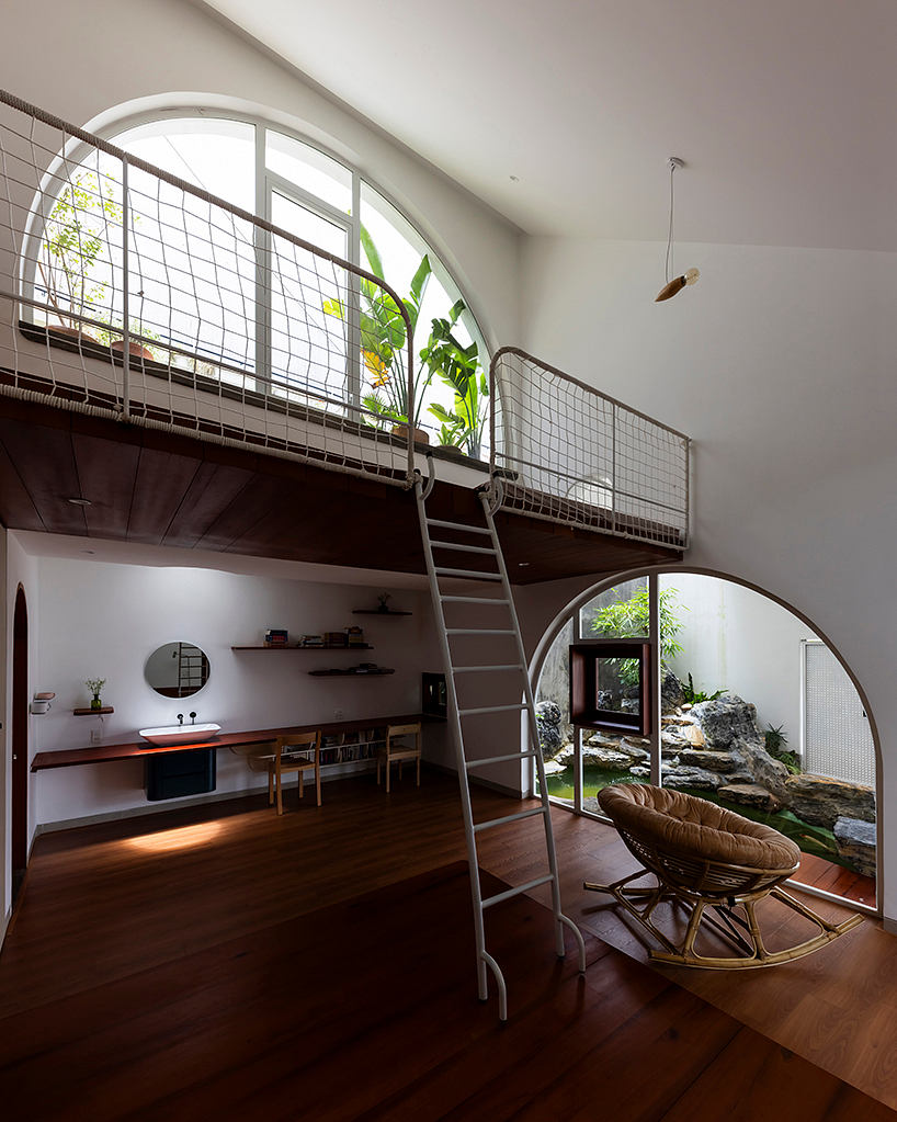 Modern loft-style space with arched window, mezzanine level, and natural elements.