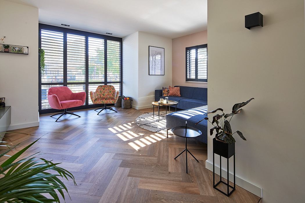 Stylish living room with plush seating, chevron wood flooring, and natural lighting.