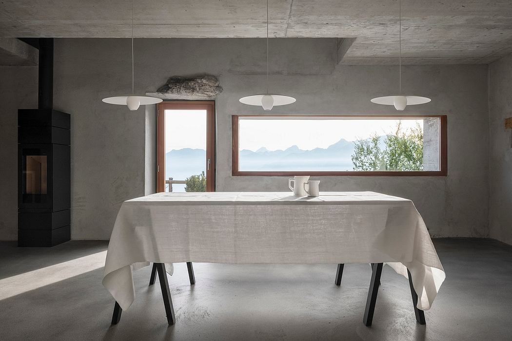 A minimalist dining room with a concrete ceiling, panoramic mountain views, and modern light fixtures.