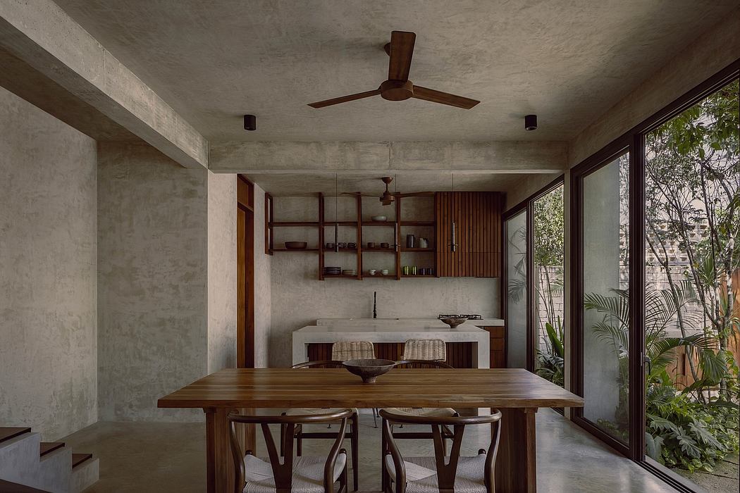 Concrete walls, wood accents, and greenery create a tranquil, modern dining space.