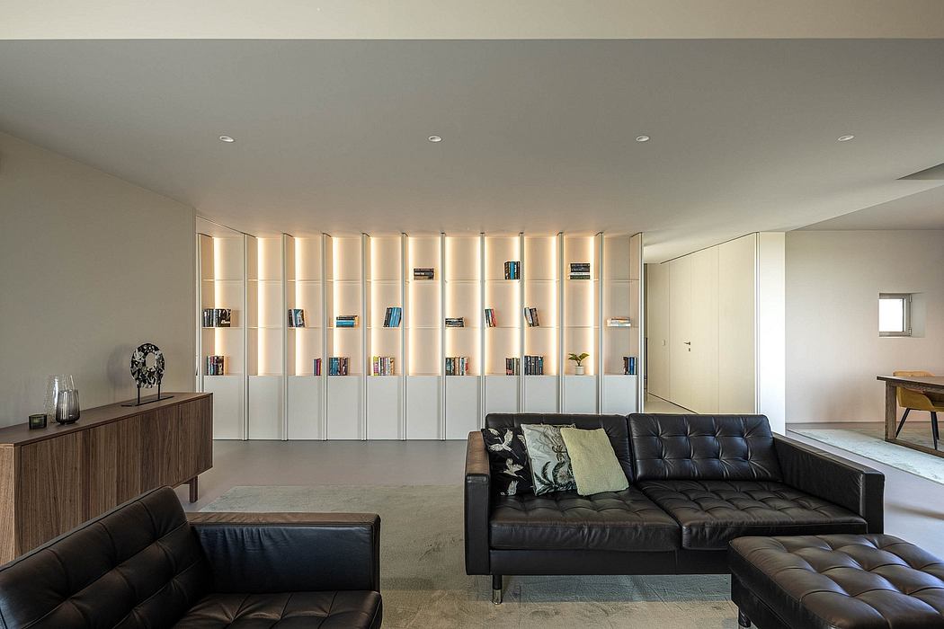 Spacious modern living room with built-in bookshelves, dark leather sofa, and warm lighting.