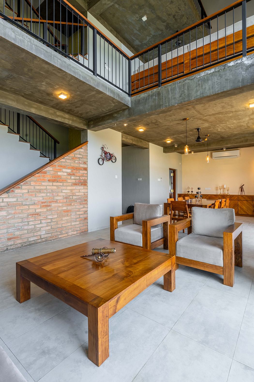 Warehouse-style open-plan living space with raw concrete ceilings, brick walls, and wooden furniture.