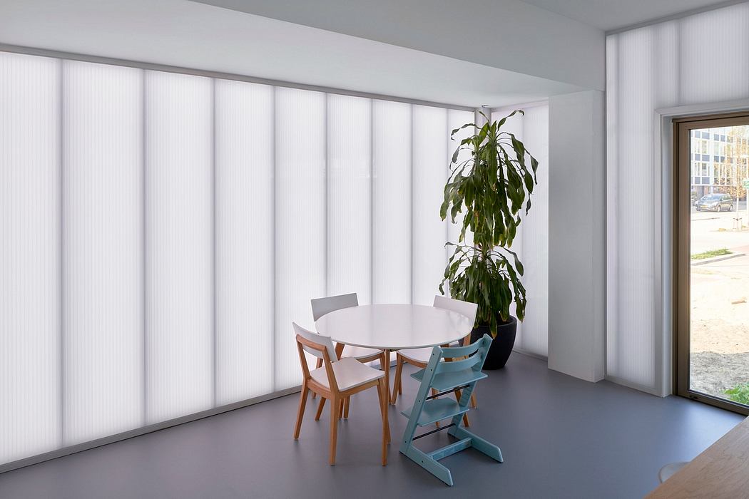 Modern dining area with minimalist furniture, large window, and potted plant.