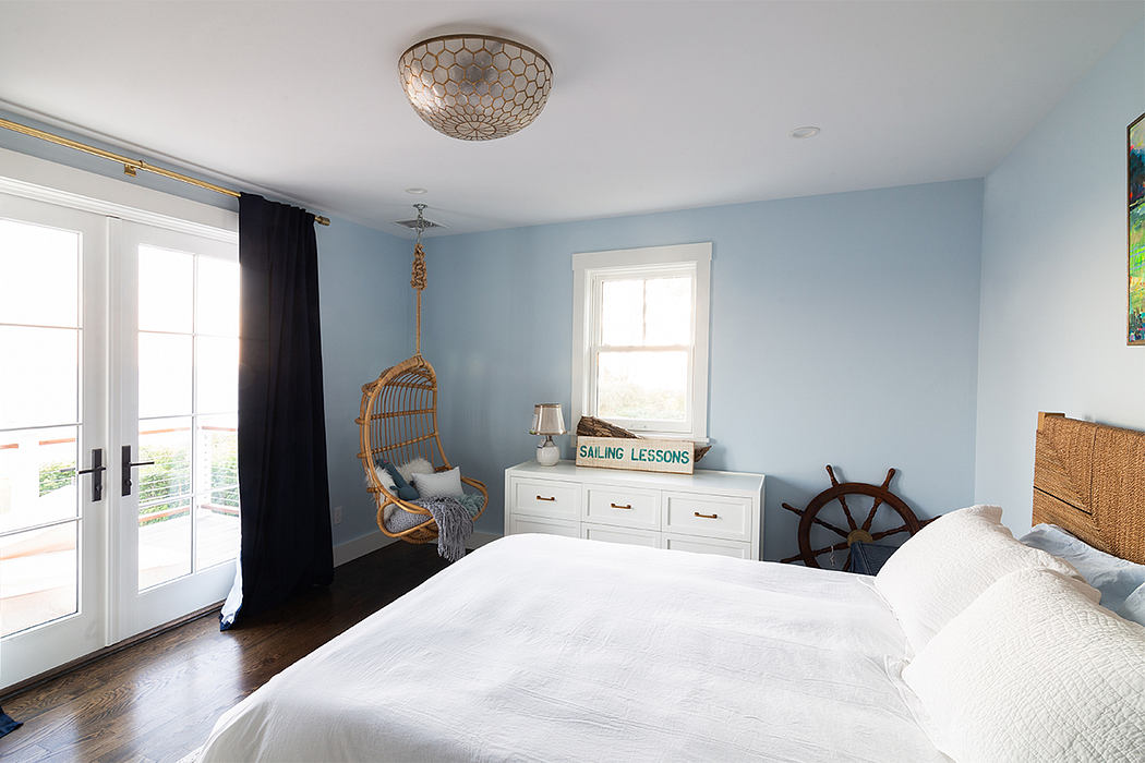 Cozy, blue-toned bedroom with hanging chair, dresser, and nautical-themed decor.