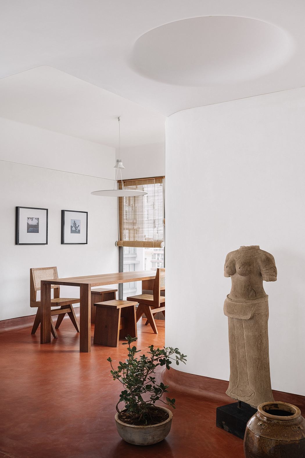 The image depicts a minimalist dining area with a wooden table, chairs, and a decorative sculpture.