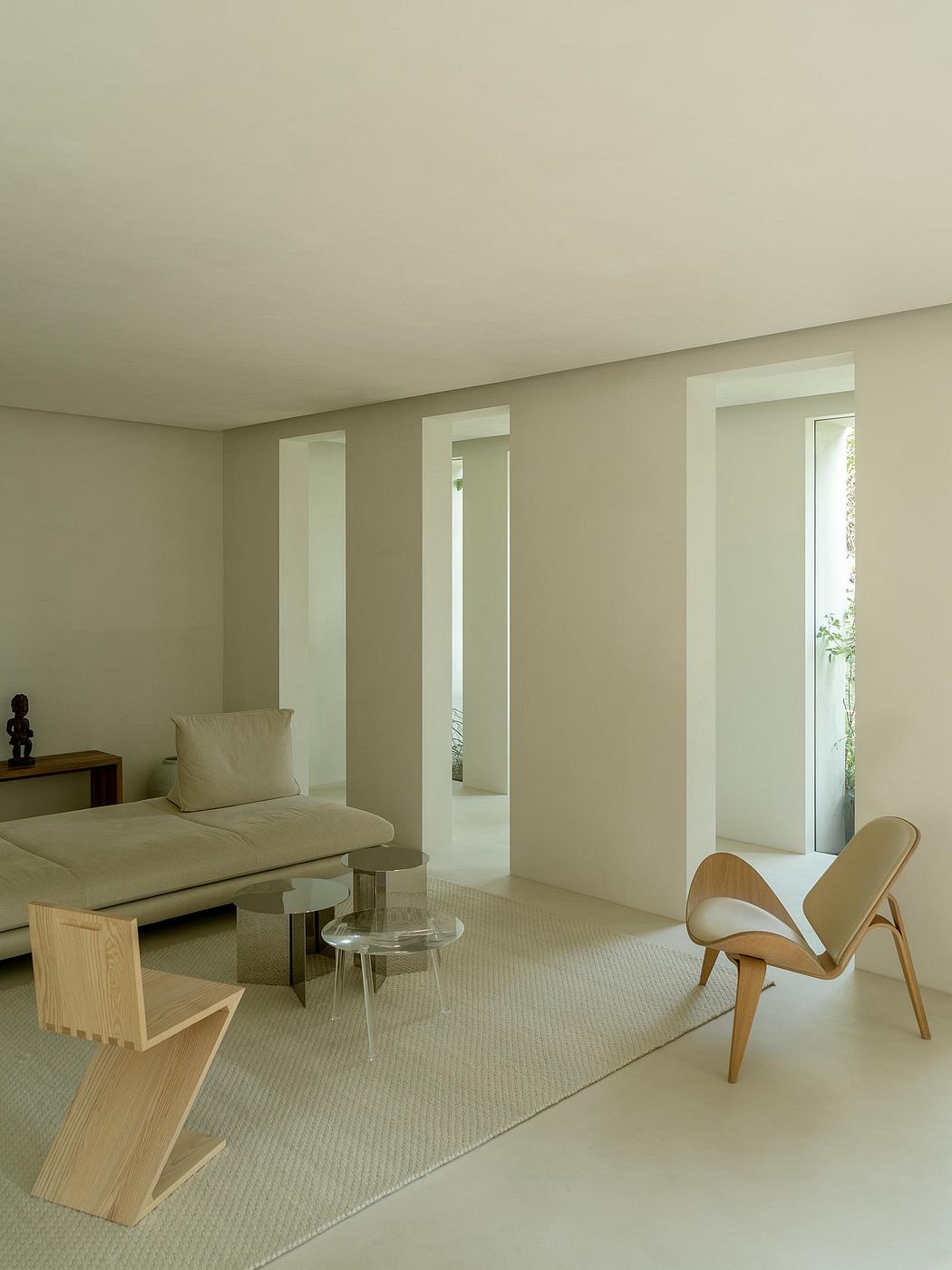 Minimalist living room with neutral-toned walls, wood furniture, and a curved lounge chair.