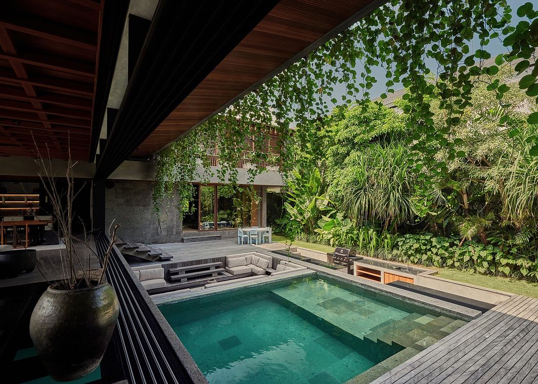 An inviting outdoor pool area with lush greenery, wooden decking, and a modern architectural design.