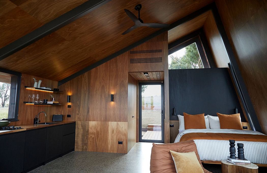 A cozy wooden cabin interior with a vaulted ceiling, pendant lighting, and a view to the outdoors.