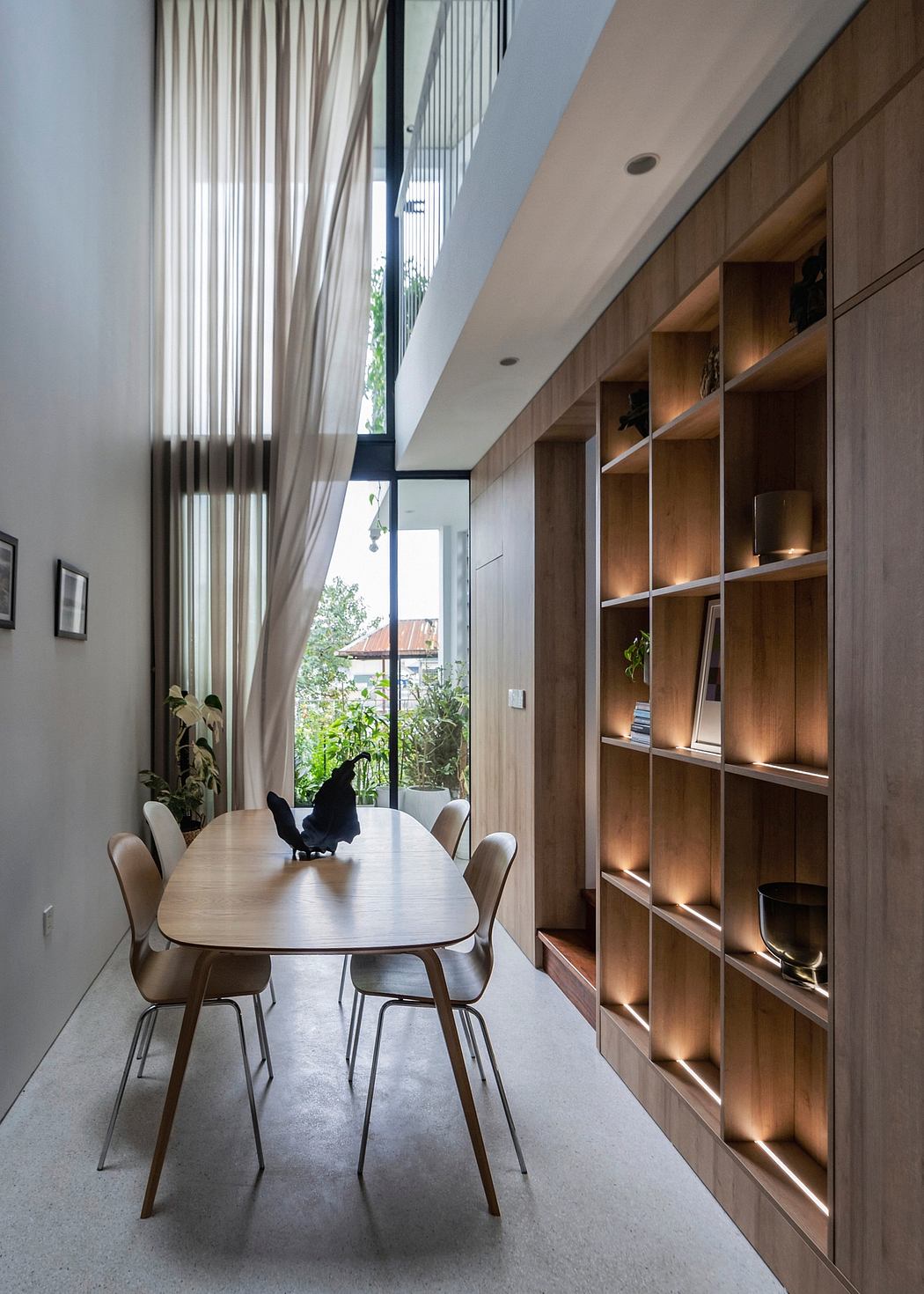 Minimalistic dining room with wood-paneled walls, shelves, and large sliding glass doors.