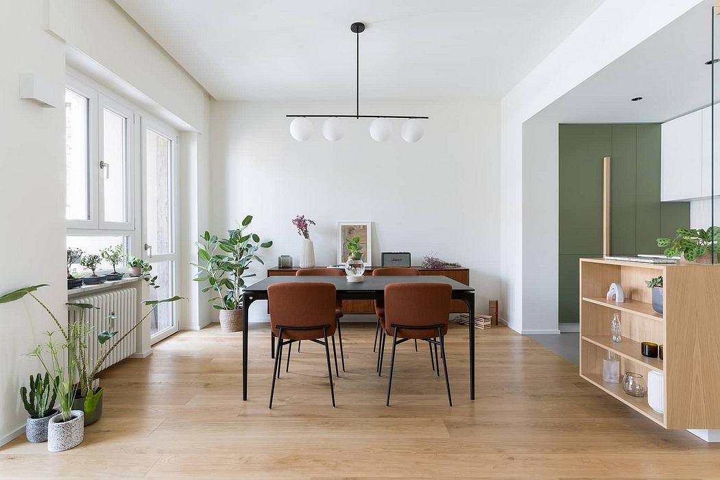 Bright, minimalist dining room with wooden table, orange chairs, and potted plants.