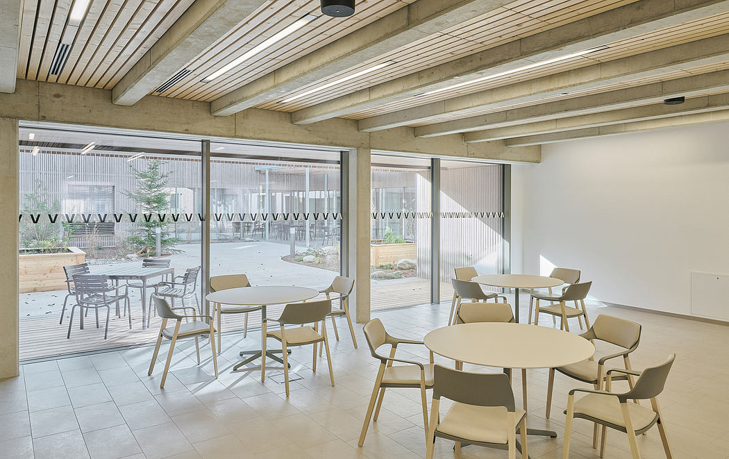An open, airy dining space with exposed wooden beams and large windows overlooking a courtyard.