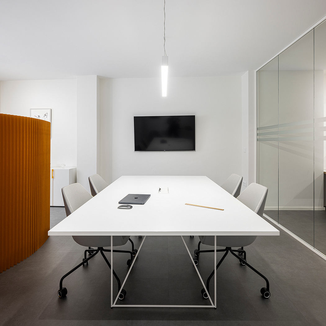 Contemporary office interior with minimalist white table, gray chairs, and wall-mounted TV.