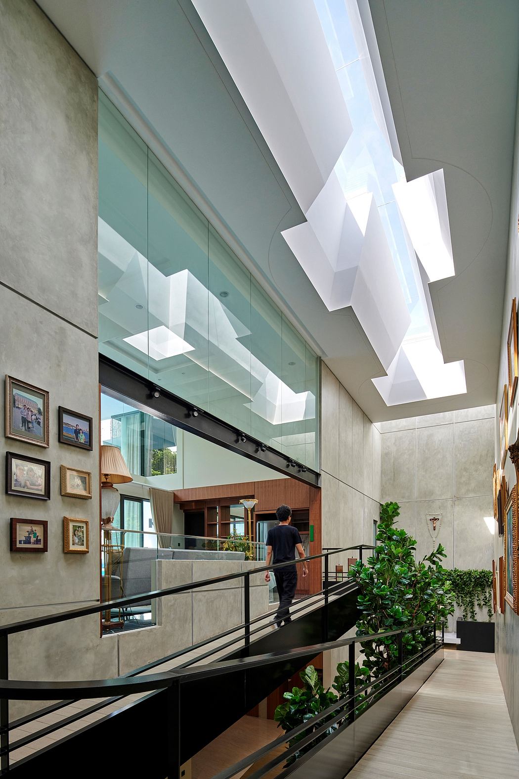 Modern, open-concept interior with sleek glass walls, geometric lighting fixtures, and lush greenery.