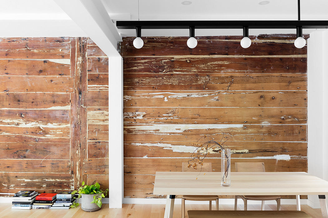 Rustic wood paneled walls, modern light fixtures, and a minimal dining setup create a warm, inviting space.