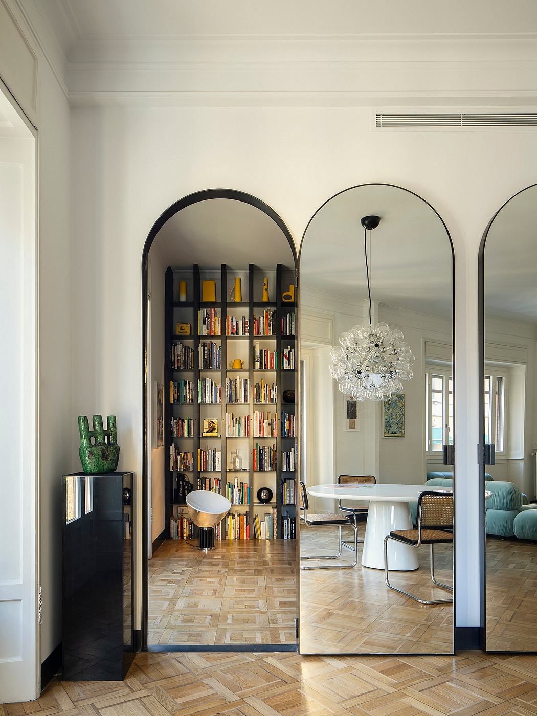 An elegant room with arched bookshelves, a white dining table, and a crystal chandelier.