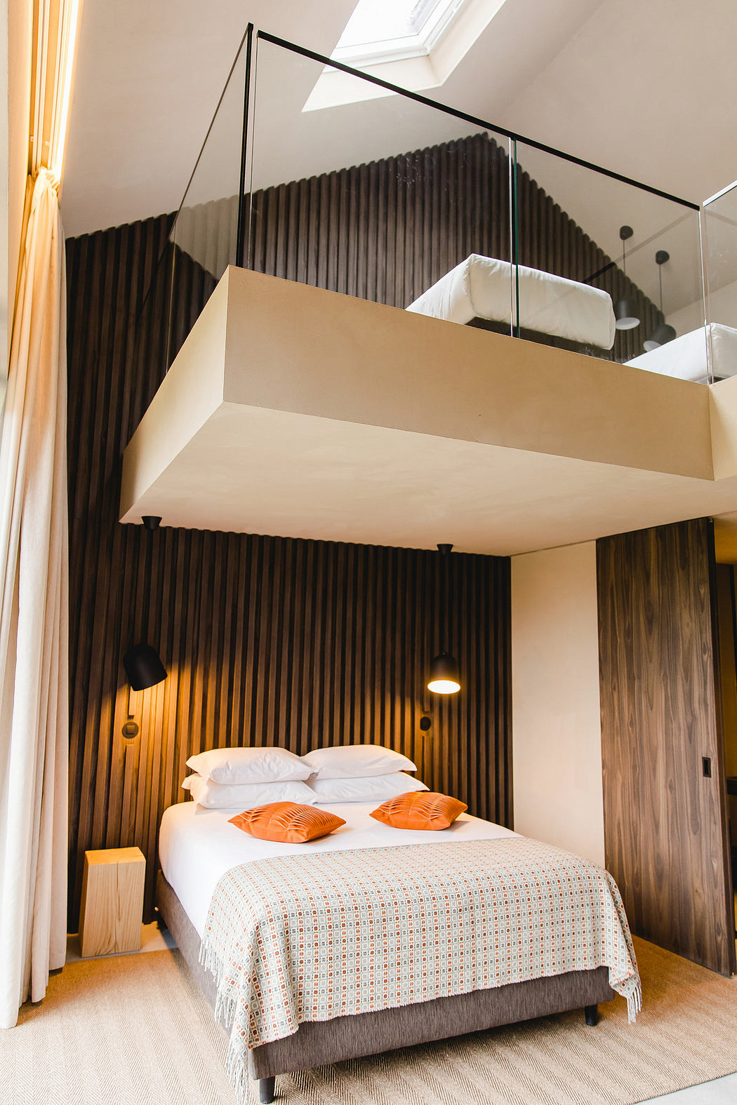 Minimalist bedroom interior with wooden panels, raised platform bed, and recessed lighting.