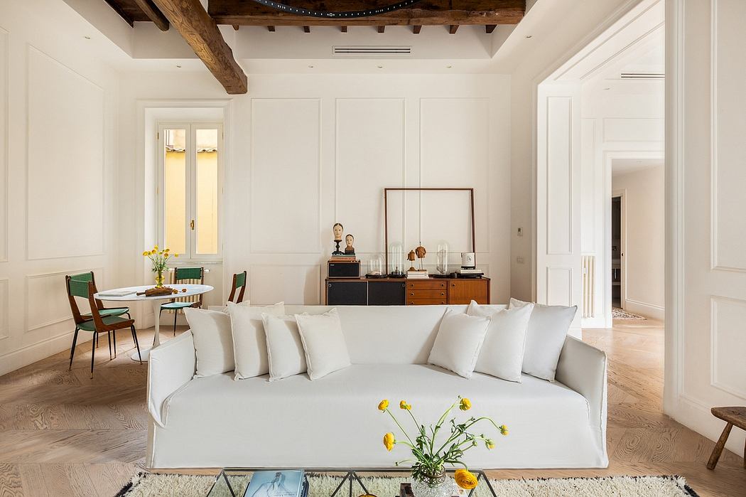 Spacious living room with exposed wooden beams, white walls, and modern furnishings.