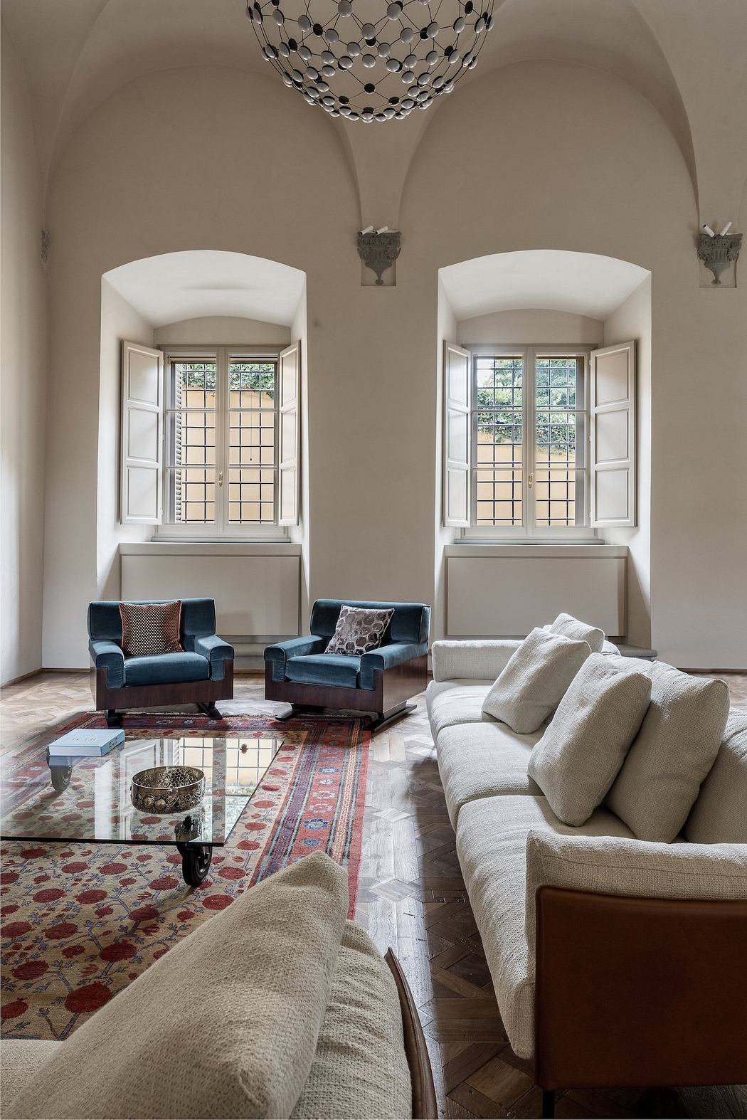 Elegant living room with arched windows, plush seating, and a striking chandelier.