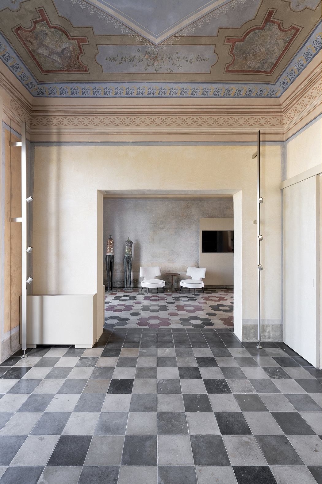 Ornate ceiling and tile flooring in a grand architectural space with minimalist seating.