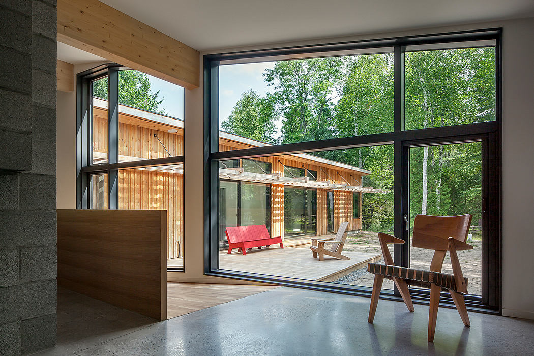 Airy, modern interior with expansive windows overlooking a lush, forested outdoor space.
