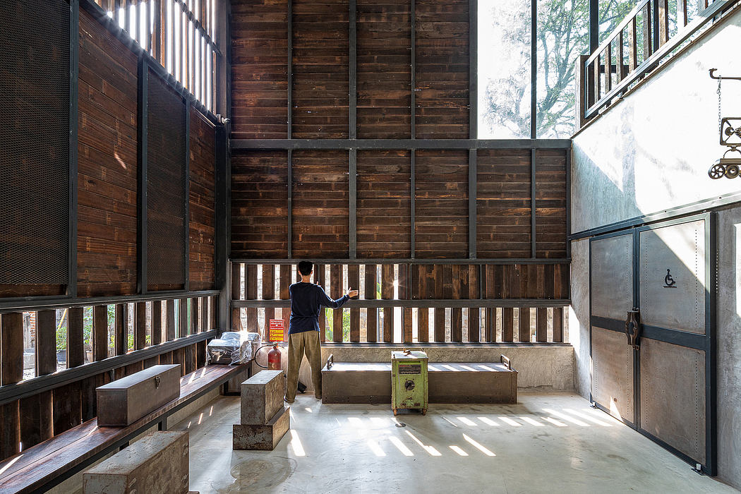 Large wooden cabin interior with exposed beams, concrete floor, and man standing at workbench.