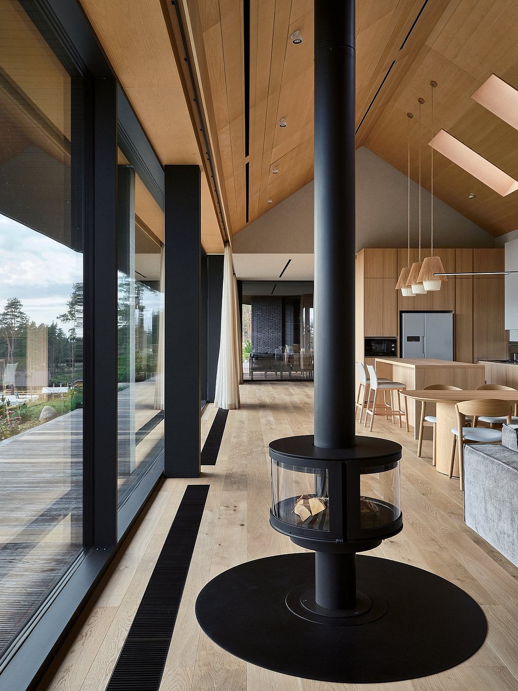 Impressive open-concept interior with wooden beams, glass walls, and a modern fireplace.