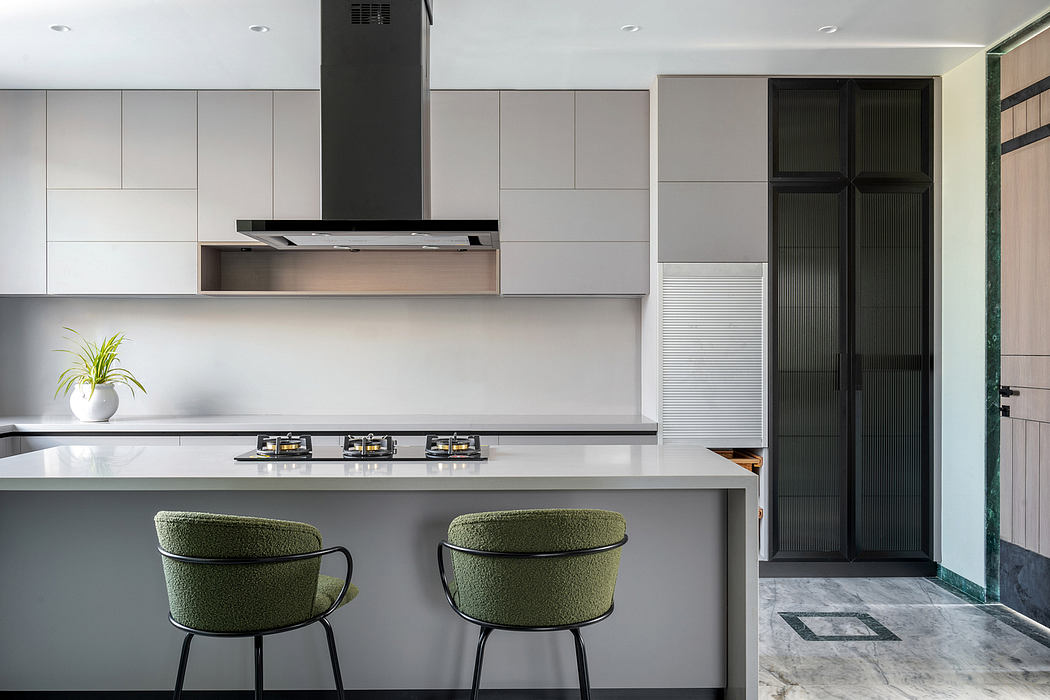 A modern kitchen with minimalist cabinetry, sleek stove, and stylish green chairs.