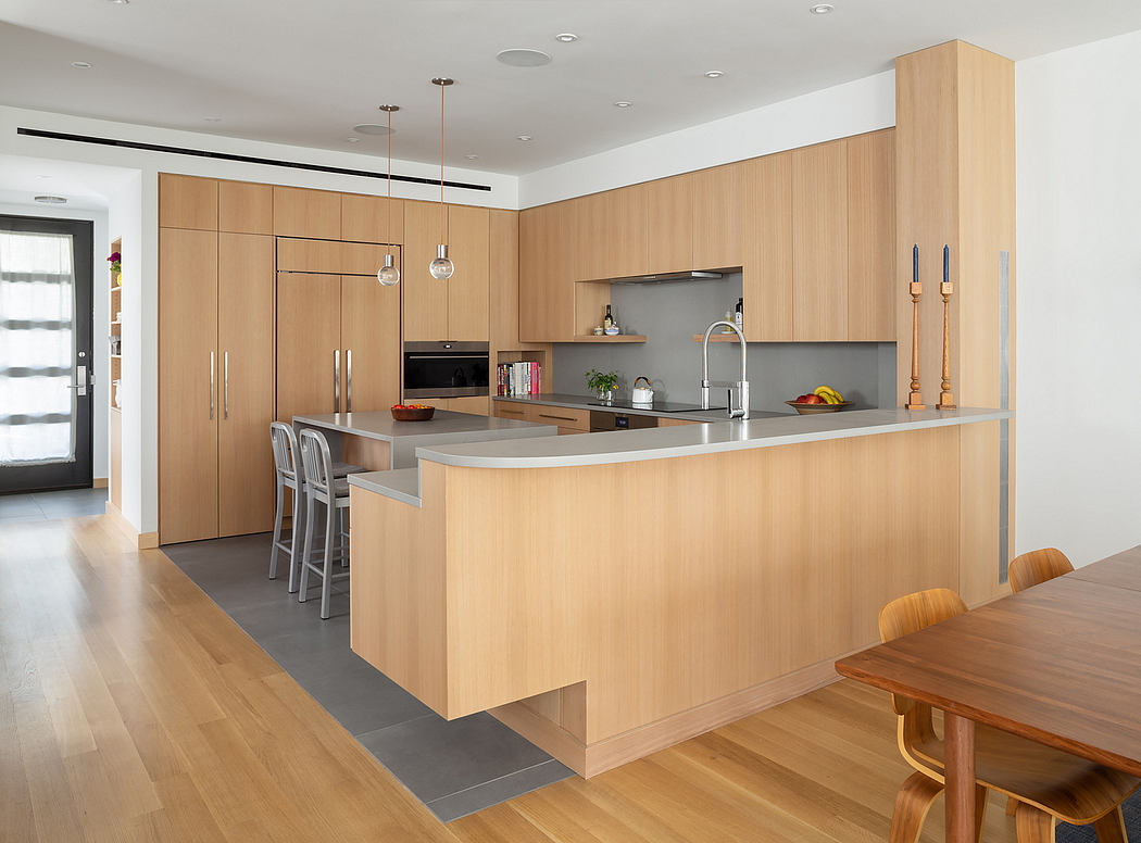 Contemporary kitchen with light wood cabinetry, stainless steel appliances, and a central island.
