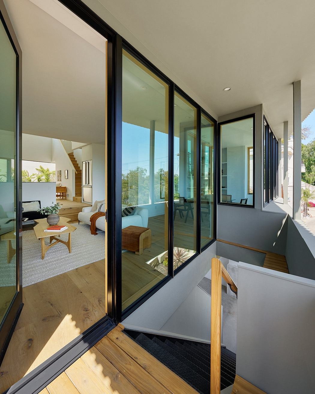 Spacious modern interior with large windows, wooden floors, and stylish furniture.